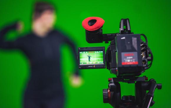 Photo of a camera pointed at a person in from of a green screen Photo by Ryan Garry on Unsplash